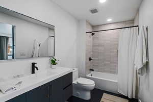 Full bathroom with toilet, vanity, and shower / bath combo with shower curtain