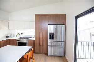 Kitchen with appliances with stainless steel finishes, light hardwood / wood-style flooring, and vaulted ceiling