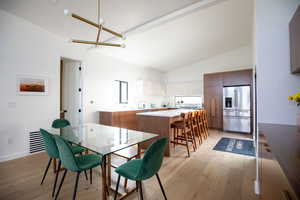 Dining room with a chandelier, light hardwood / wood-style floors, and lofted ceiling