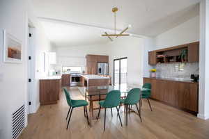 Dining room featuring high vaulted ceiling, light hardwood / wood-style floors, and an inviting chandelier