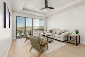 Living area featuring ceiling fan, light wood-type flooring, baseboards, and a raised ceiling