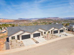 View of front of property featuring stucco siding, a mountain view, driveway, stone siding, and an attached garage