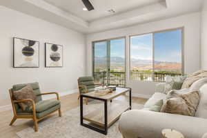 Living room featuring a tray ceiling, a mountain view, visible vents, light wood finished floors, and baseboards