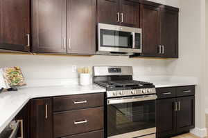Kitchen with dark brown cabinetry, light countertops, and stainless steel appliances