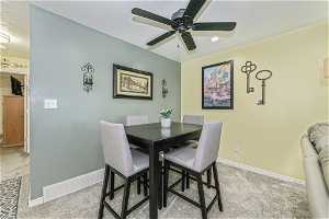 Carpeted dining area featuring ceiling fan