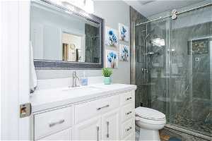 Bathroom with walk in shower, toilet, and vanity with extensive cabinet space