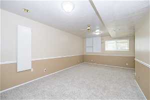 Unfurnished room featuring light carpet, ceiling fan, and a textured ceiling