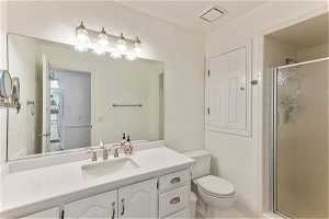 Bathroom with a shower with door, tile floors, toilet, and vanity with extensive cabinet space