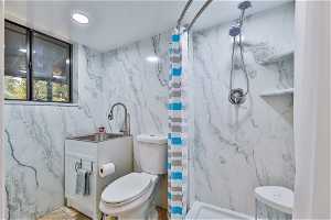 Bathroom featuring a shower with curtain, sink, and toilet