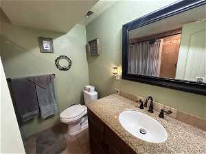 Basement Bathroom with oversized vanity, toilet, with tiled floors & tub surrounds