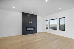 Unfurnished living room featuring light hardwood / wood-style floors and a large fireplace