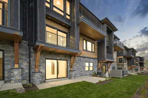 Back of house with a patio area, a lawn, a balcony, and central AC unit