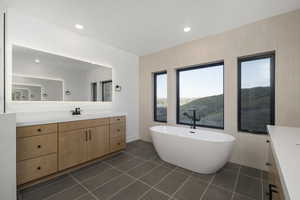 Bathroom featuring tile walls, vanity, a tub to relax in, and tile patterned flooring