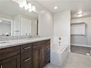Bathroom with a bath, dual vanity, and tile floors