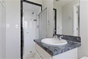 Bathroom featuring tile flooring, oversized vanity, and a shower with door