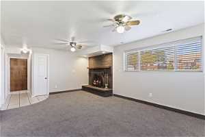 Unfurnished living room with a fireplace, ceiling fan, light carpet, and a textured ceiling