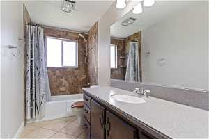 Full bathroom featuring tile flooring, toilet, vanity with extensive cabinet space, and shower / bath combo with shower curtain