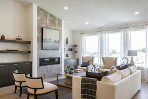 Living room featuring built in shelves, light hardwood / wood-style flooring, and a tile fireplace. Note: This Is Not The Subject Property Itself