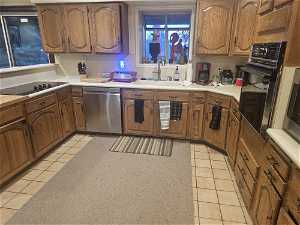 Kitchen featuring black appliances, sink, and light tile flooring