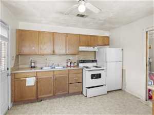Kitchen with backsplash, white appliances, ceiling fan, sink, and light tile floors
