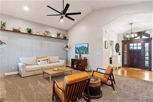 Carpeted living room featuring high vaulted ceiling and ceiling fan