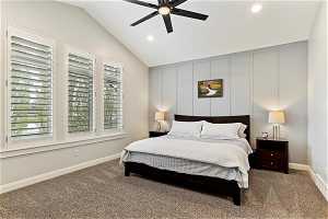 Carpeted bedroom with ceiling fan and vaulted ceiling, and accent wall