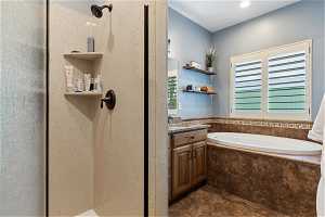 Bathroom featuring vanity, tiled tub, and tile flooring