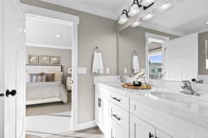 Bathroom with dual sinks, crown molding, and large vanity