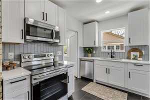 Kitchen with appliances with stainless steel finishes, plenty of natural light, sink, and backsplash