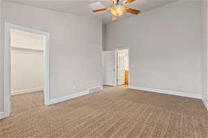 Primary master suite featuring a spacious closet, high vaulted ceiling, ceiling fan, and light carpet