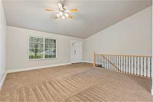 Upstairs entertaining space featuring light colored carpet, lofted ceiling, and ceiling fan