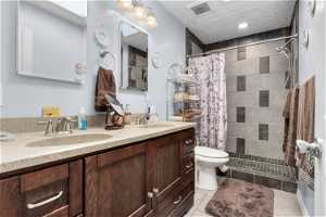 Master Bathroom featuring toilet, curtained shower, tile floors, dual vanity, and a textured ceiling