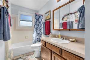 Full bathroom featuring vanity, shower / bath combination with curtain, toilet, and tile flooring