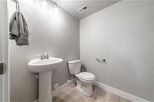 Bathroom featuring wood-type flooring, a textured ceiling, sink, and toilet