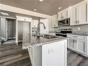 Kitchen featuring appliances with stainless steel finishes, white cabinetry, and dark wood-type flooring