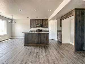 Kitchen featuring appliances with stainless steel finishes, dark brown cabinetry, and hardwood / wood-style floors