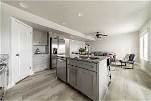 Kitchen featuring gray cabinetry, light hardwood / wood-style flooring, sink, and an island with sink