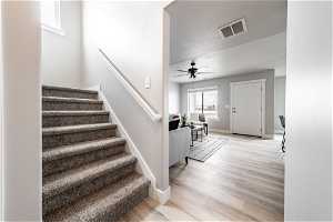 Stairs with ceiling fan, light hardwood / wood-style flooring, and a textured ceiling