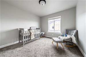 Bedroom with a nursery area, light carpet, and lofted ceiling