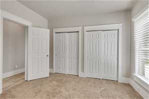Unfurnished bedroom featuring light colored carpet and two closets