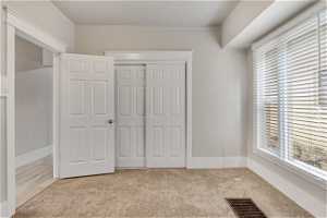 Unfurnished bedroom with a closet, light carpet, and multiple windows