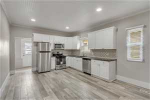 Kitchen with white cabinets, sink, appliances with stainless steel finishes, and backsplash