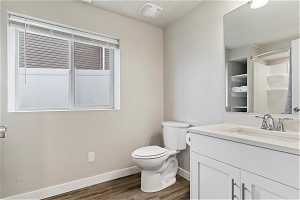 Bathroom with hardwood / wood-style flooring, toilet, and oversized vanity