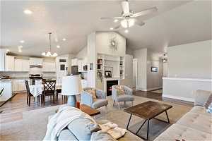 Living room with high vaulted ceiling, light hardwood / wood-style flooring, and ceiling fan with notable chandelier
