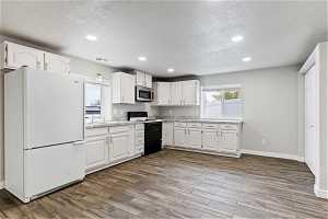 Kitchen featuring white cabinets, hardwood / wood-style floors, white appliances, and a textured ceiling