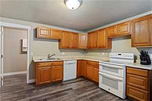 Kitchen featuring dark wood-type flooring, sink, a textured ceiling, and white appliances