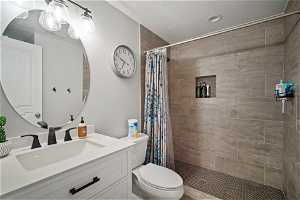 Bathroom featuring oversized vanity, curtained shower, and toilet