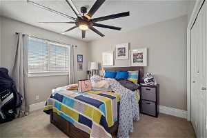Bedroom with a closet, light carpet, and ceiling fan
