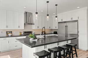 Kitchen with wall chimney exhaust hood, pendant lighting, light hardwood / wood-style flooring, and range