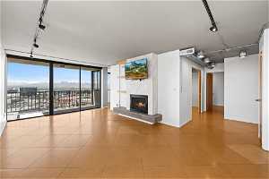 Unfurnished living room with floor to ceiling windows, light tile flooring, rail lighting, and a premium fireplace